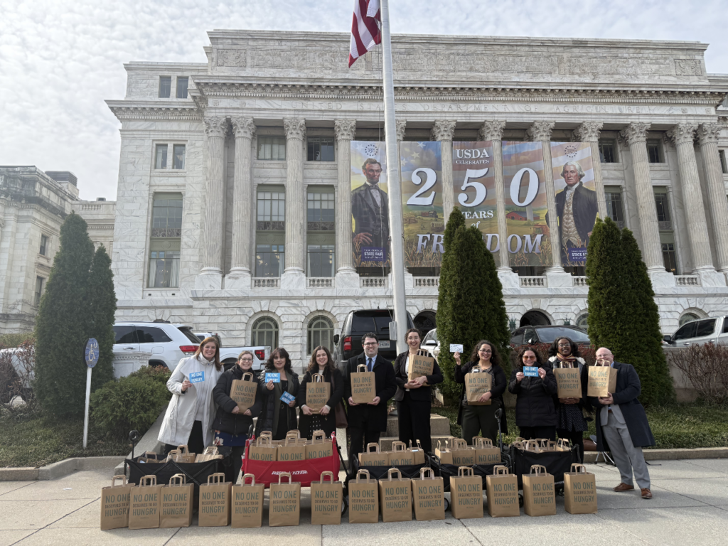 Group of people in front of USDA building holding bags of postcards
