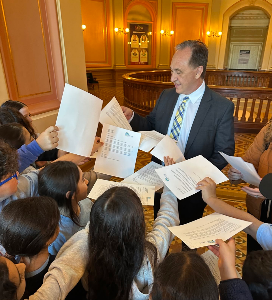 Students around lawmaker with papers