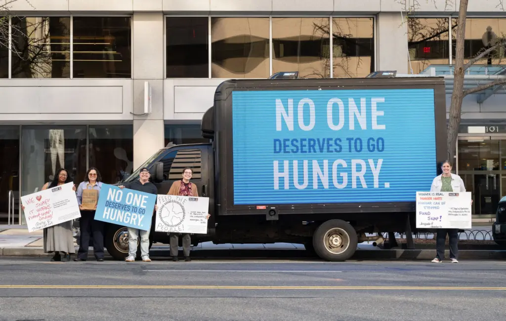 Mobile billboard truck with people standing
