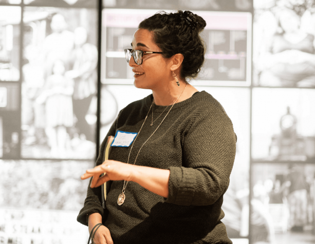 Woman speaking at event in front of art wall